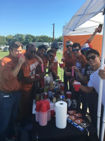 Texas vs OU - Burnt orange crew raising cups at the tailgate bar - Dallas VIP