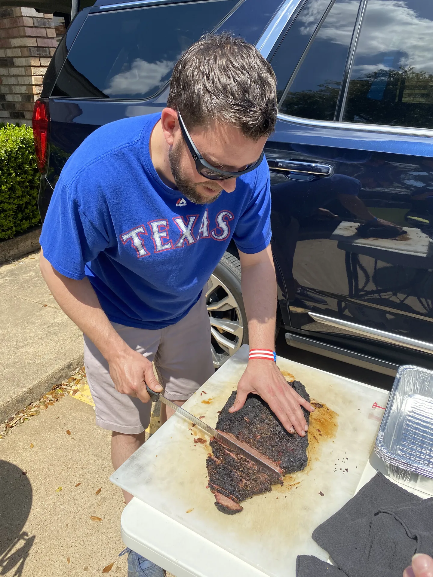 Corporate Tailgate - Pitmaster slicing a smoked brisket beside the SUV before first pitch - DallasVIP