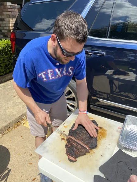 Corporate Tailgate - Pitmaster slicing a smoked brisket beside the SUV before first pitch - DallasVIP
